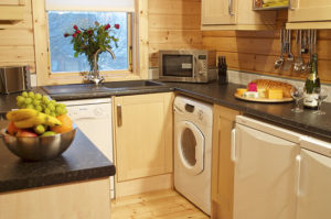 interior view of a lodge's kitchen with modern appliances and wooden cabinets.